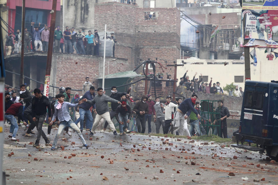 Protestors throw stones during a clash between communities while protesting against Thursday's attack on a paramilitary convoy that killed at least 40 in Kashmir, in Jammu, India, Friday, Feb. 15, 2019. Prime Minister Narendra Modi placed the blame for Thursday's bombing squarely on neighboring Pakistan, which India accuses of supporting rebels in Kashmir. The attack has raised tensions elsewhere in Hindu-majority India. Hundreds of residents carrying India's national flag in Hindu-dominated Jammu city in the Muslim-majority state burned vehicles and hurled rocks at homes in Muslim neighborhoods, officials said. (AP Photo/Channi Anand)