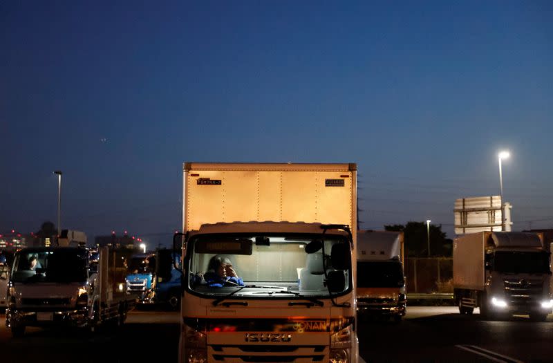 Delivery trucks are parked at a parking area along the highway in Chiba