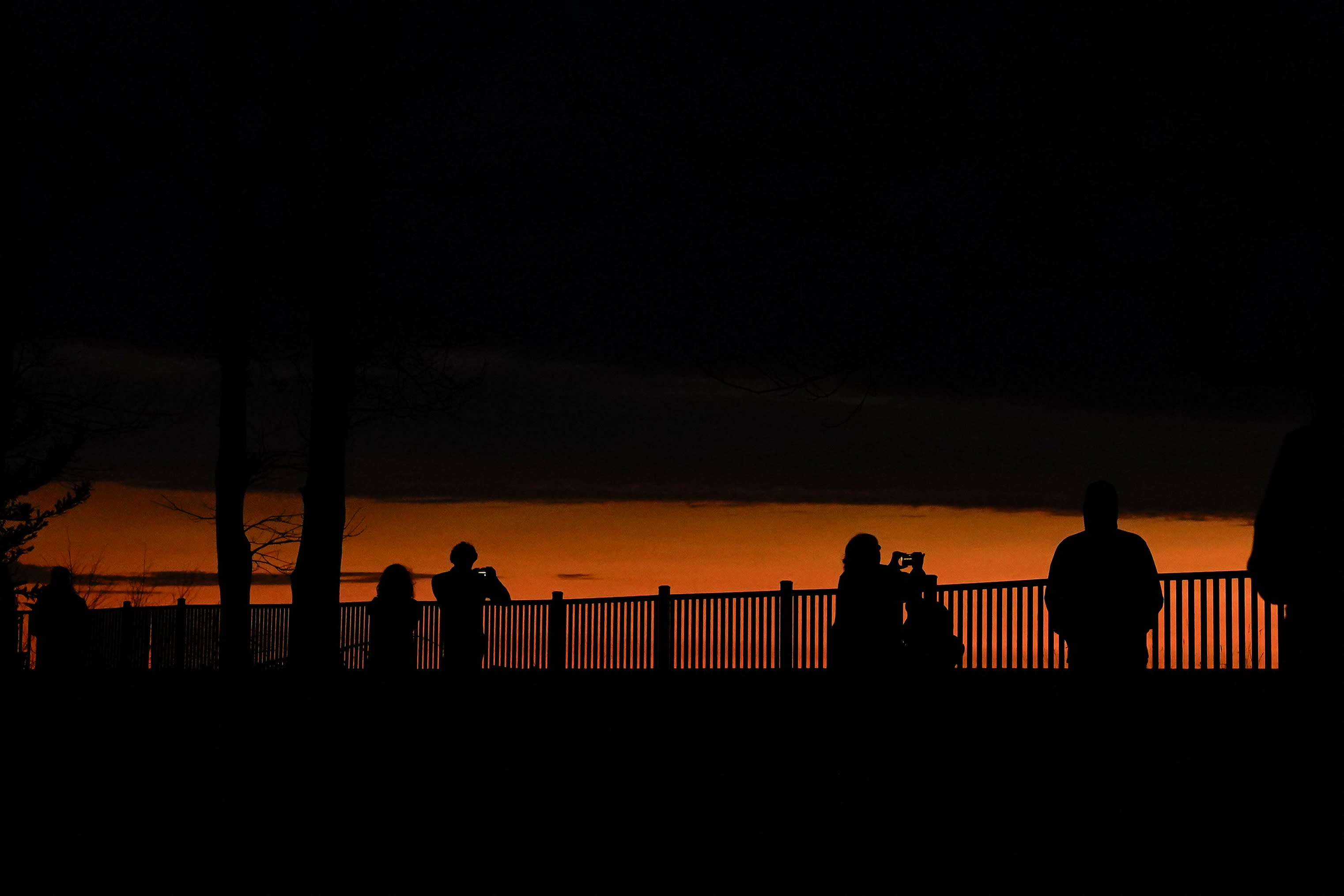 People look out towards Lake Erie and the horizon during a total solar eclipse under cloudy conditions seen from Dunkirk Lighthouse & Veterans Park Museum in Dunkirk, New York on April 8, 2024. (Elizabeth Frantz/Reuters)