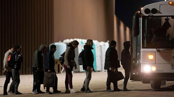 PHOTO: Asylum-seekers board a bus after being processed by US Customs and Border Patrol agents at a gap in the US-Mexico border fence near Somerton, Arizona, Dec. 26, 2022. (Rebecca Noble/AFP via Getty Images)