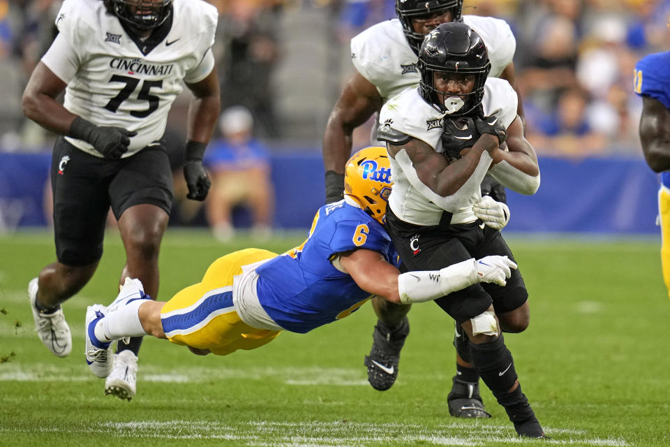 Cincinnati running back Corey Kiner, right, is tackled by Pittsburgh defensive lineman Nate Temple (6) during the first half of an NCAA college football game in Pittsburgh on Saturday, Sept. 9, 2023. (AP Photo/Gene J. Puskar)