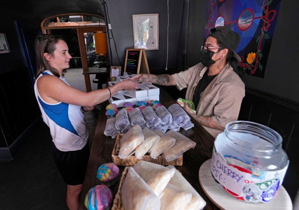 Chase Roldan, right, co-owner of Milwaukee's Moon Cherry Sweets, sells baked goods to Laura Hedden, of West Allis, at the plant-based pop-up bakery at the Cactus Club in Milwaukee.