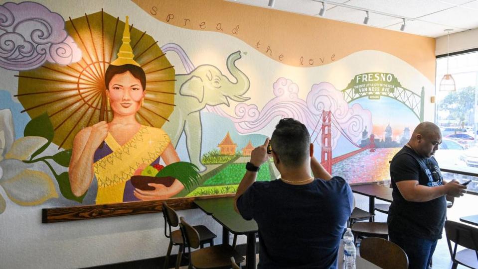 A customer photographs the new mural at Love & Thai, which is having a soft opening in the shopping center at South Chestnut and East Butler avenues in southeast Fresno.