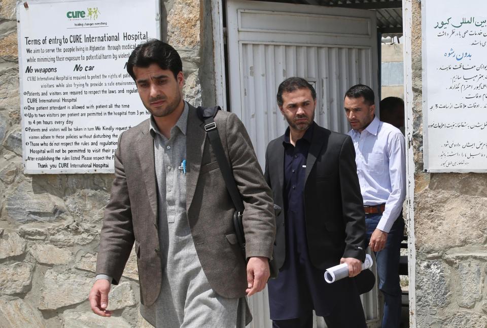 Afghan civilians walk out from a gate of Cure International Hospital in Kabul, Afghanistan, Thursday, April 24, 2014. (AP Photo/Massoud Hossaini)