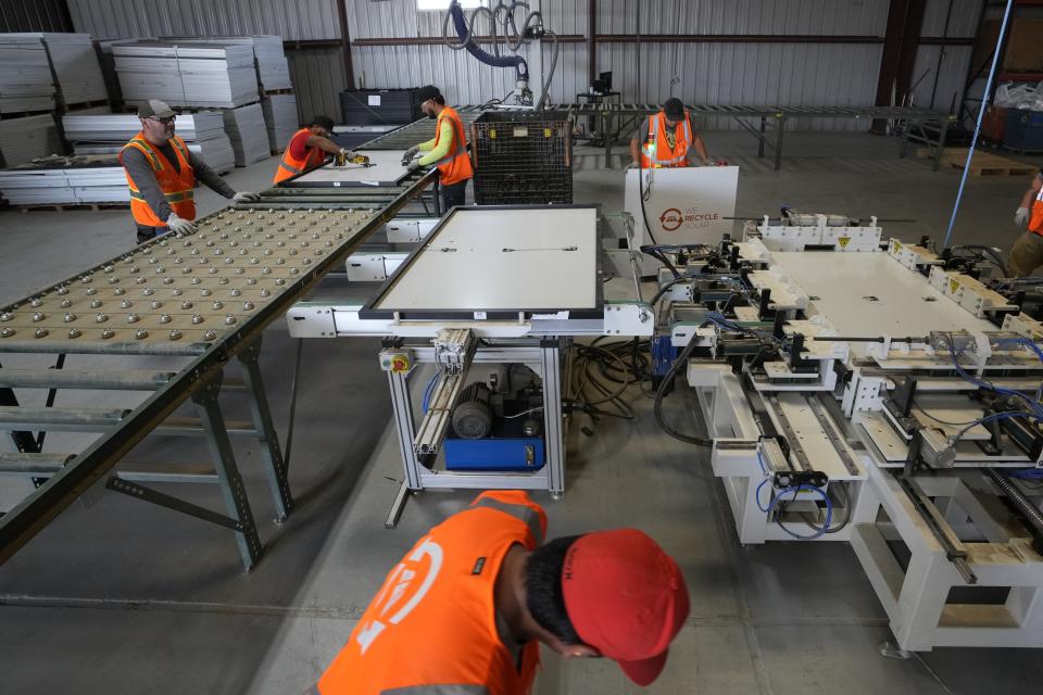 Workers take apart solar panels as they begin the recycling process at We Recycle Solar on Tuesday, June 6, 2023, in Yuma, Ariz. North America’s first utility-scale solar panel recycling plant opened to address what founders of the company call a “tsunami” of solar waste, as technology that became popular in the early 2000s rapidly scales up. (AP Photo/Gregory Bull)