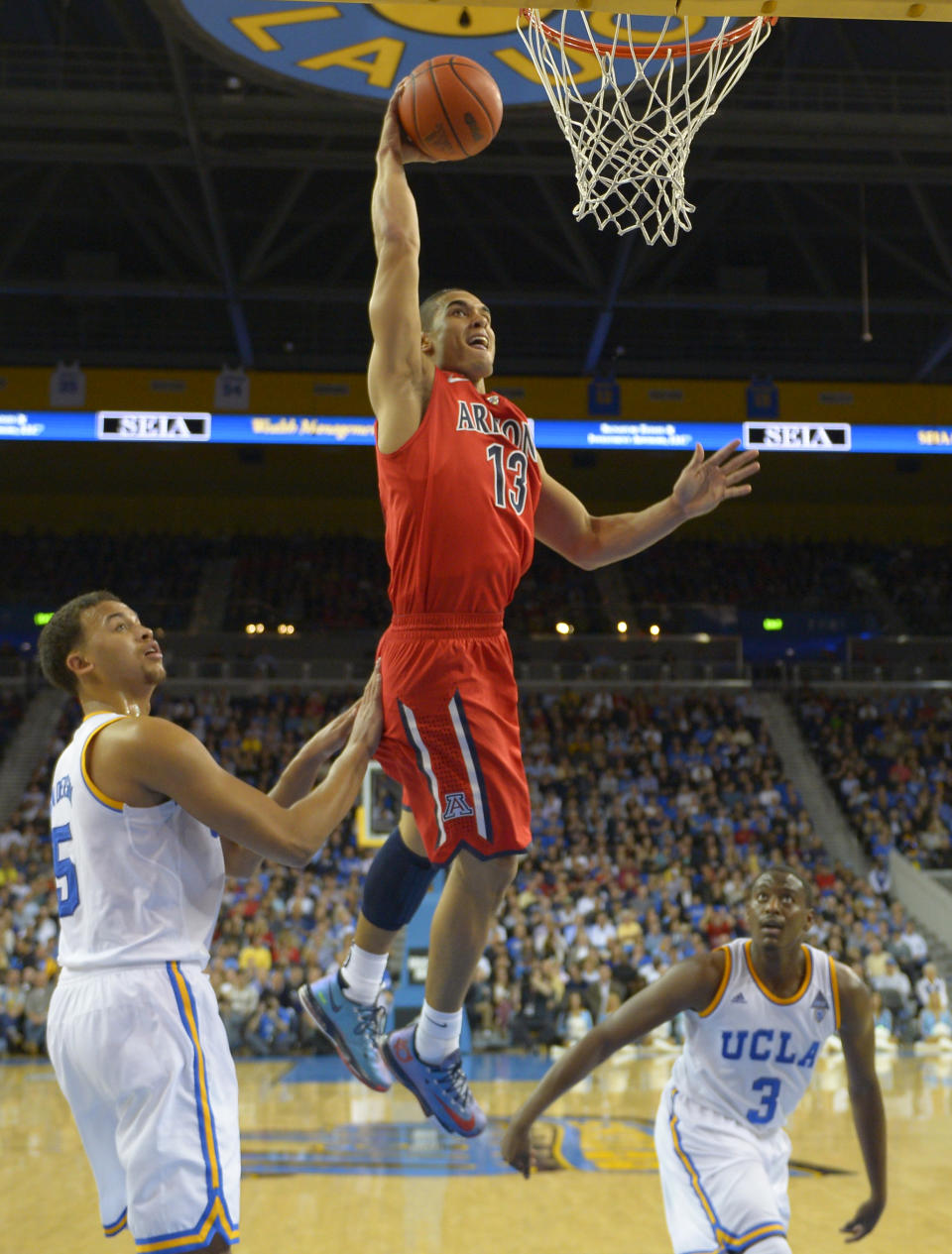 Arizona guard Nick Johnson, center, goes up to dunk as UCLA forward Kyle Anderson, left, and guard Jordan Adams defend during the second half of an NCAA college basketball game on Thursday, Jan. 9, 2014, in Los Angeles. (AP Photo/Mark J. Terrill)