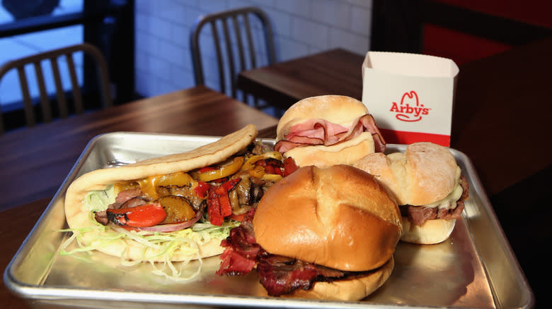Variety of Arby's food on metal tray in dimly lit restaurant