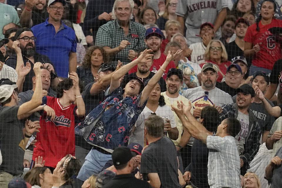 Fans reach for a foul ball hit by Philadelphia Phillies' Trea Turner in the sixth inning of a baseball game against the Cleveland Guardians, Friday, July 21, 2023, in Cleveland. (AP Photo/Sue Ogrocki)