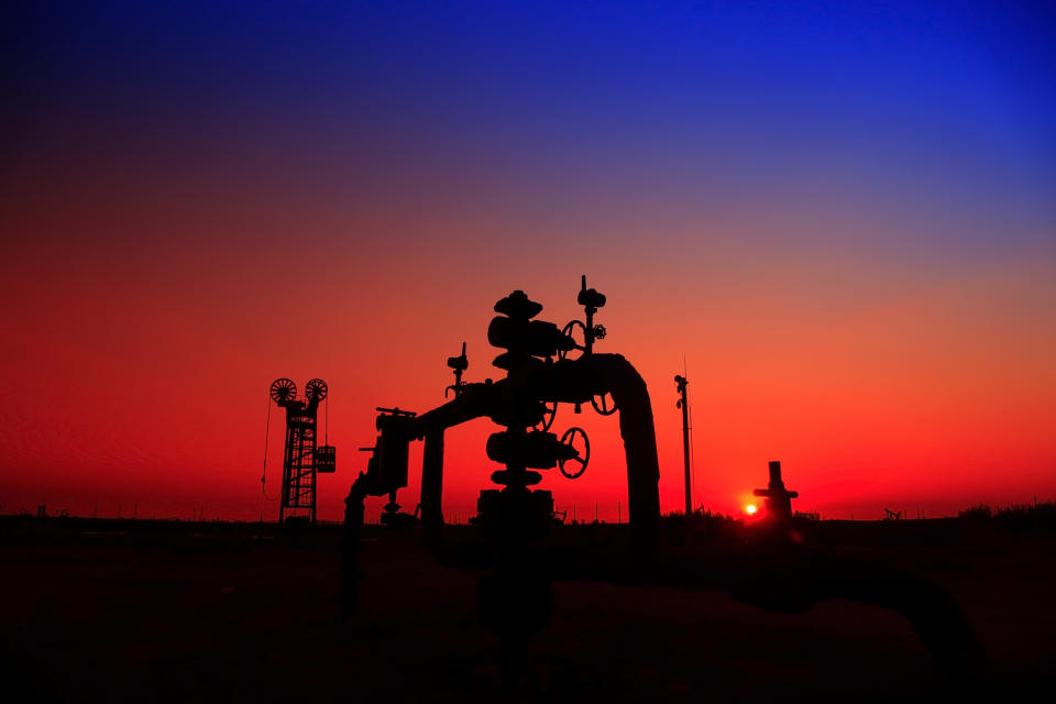 A natural gas well with pipelines at sunset