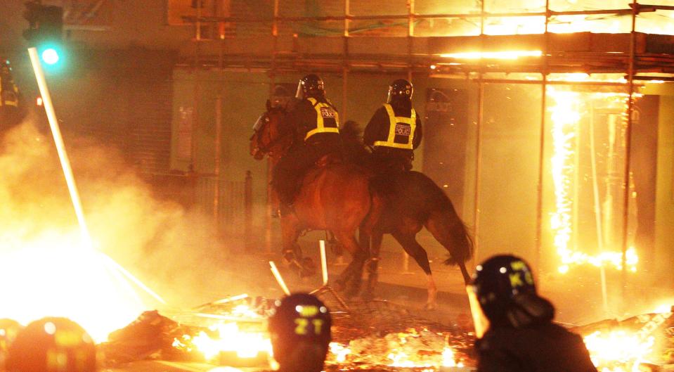 File photo of mounted police on the streets in Tottenham, north London as fire burns around them during riots. (Lewis Whyld/PA) (PA Archive)