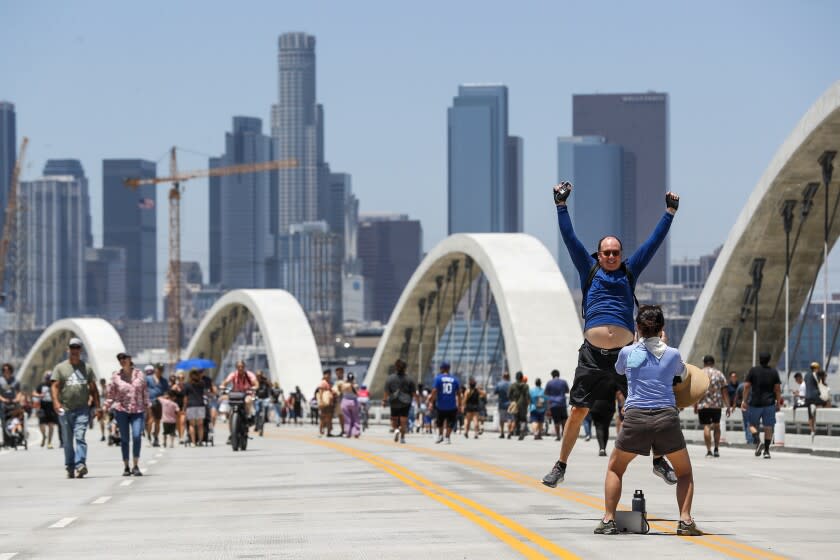 Los Angeles, CA, Sunday, July 10, 2022 - John Lopker leaps for a photo by Hae Jeong Kim as they visit the Sixth Street Viaduct, downtown. (Robert Gauthier/Los Angeles Times)