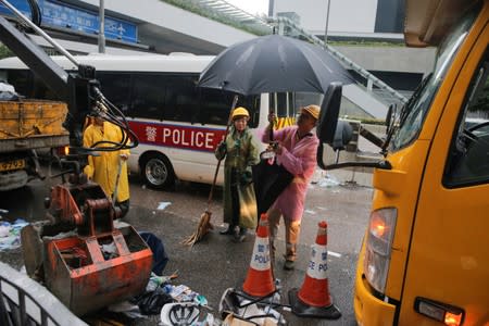 Street cleaners collect rubbish left behind after violent clashes during a protest against a proposed extradition bill with China in Hong Kong