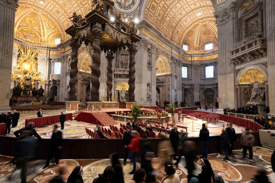 People look at the body of the late Pope Emeritus Benedict XVI laid out in state Monday inside St. Peter's Basilica at the Vatican. Benedict XVI, the German theologian who will be remembered as the first pope in 600 years to resign, died Saturday. He was 95.