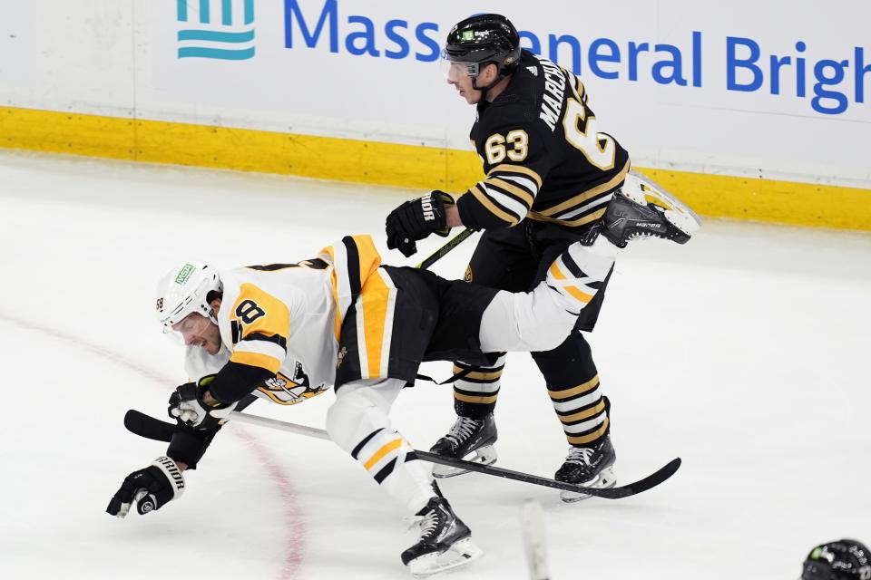 Boston Bruins' Brad Marchand (63) trips Pittsburgh Penguins' Kris Letang (58) during the first period of an NHL hockey game, Saturday, March 9, 2024, in Boston. (AP Photo/Michael Dwyer)