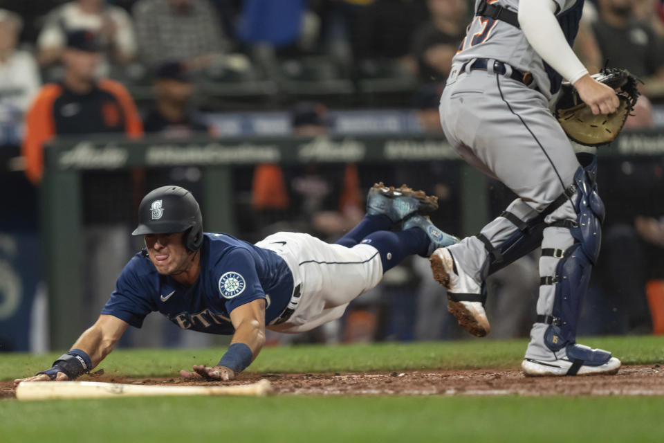 Seattle Mariners' Dylan Moore, left, slides safely into home plate to score a run on a hit by Adam Frazier off Detroit Tigers starting pitcher Bryan Garcia during the fifth inning of a baseball game, Monday, Oct. 3, 2022, in Seattle. (AP Photo/Stephen Brashear)