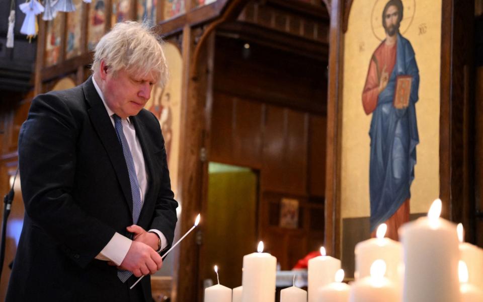  Boris Johnson lights a candle during the ecumenical prayer service at Ukrainian Catholic Cathedral, in London - AFP