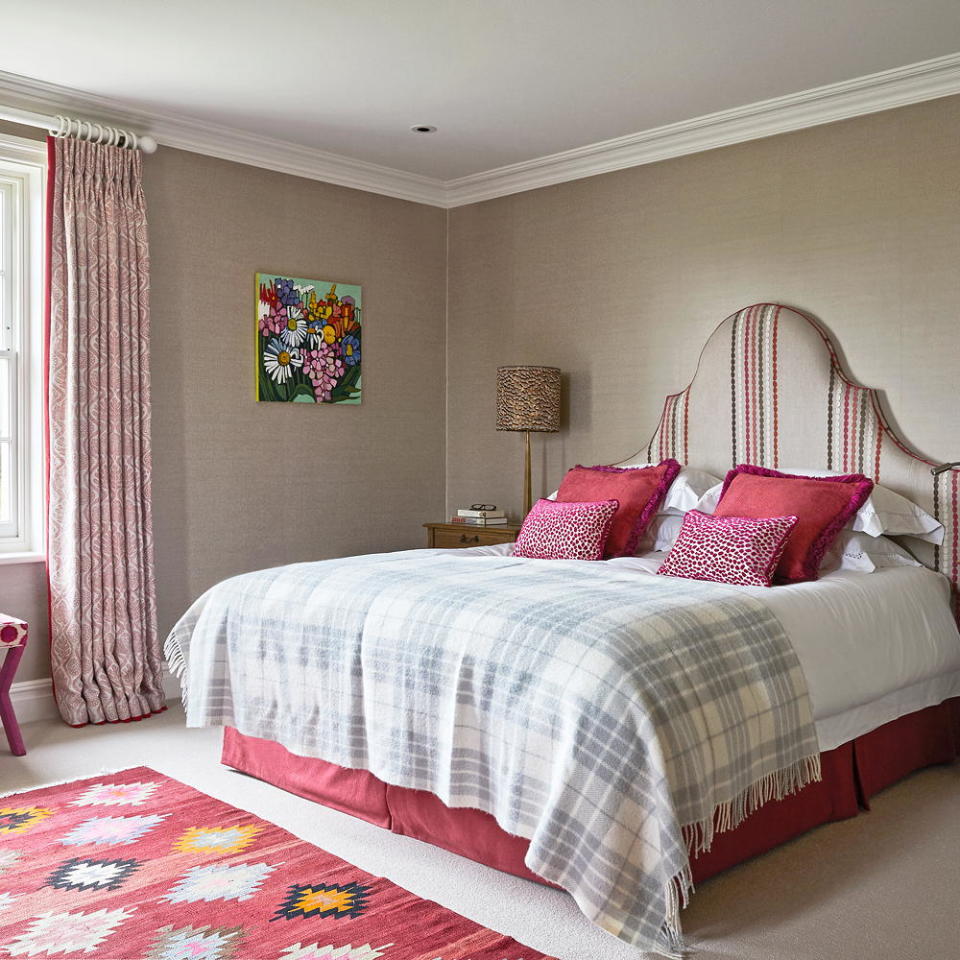 bedroom with pink rug cushions and floral painting