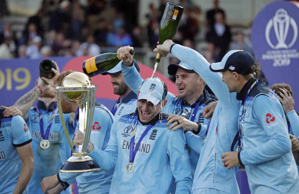 England's captain Eoin Morgan is doused with champagne as he raises the trophy after winning the Cricket World Cup final match between England and New Zealand at Lord's cricket ground in London, Sunday, July 14, 2019. England won after a super over after the scores ended tied after 50 overs each. (AP Photo/Matt Dunham)