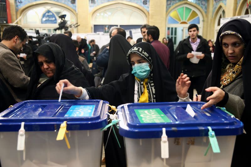 Woman wears a face mask as she casts her vote during parliamentary elections at a polling station in Tehran