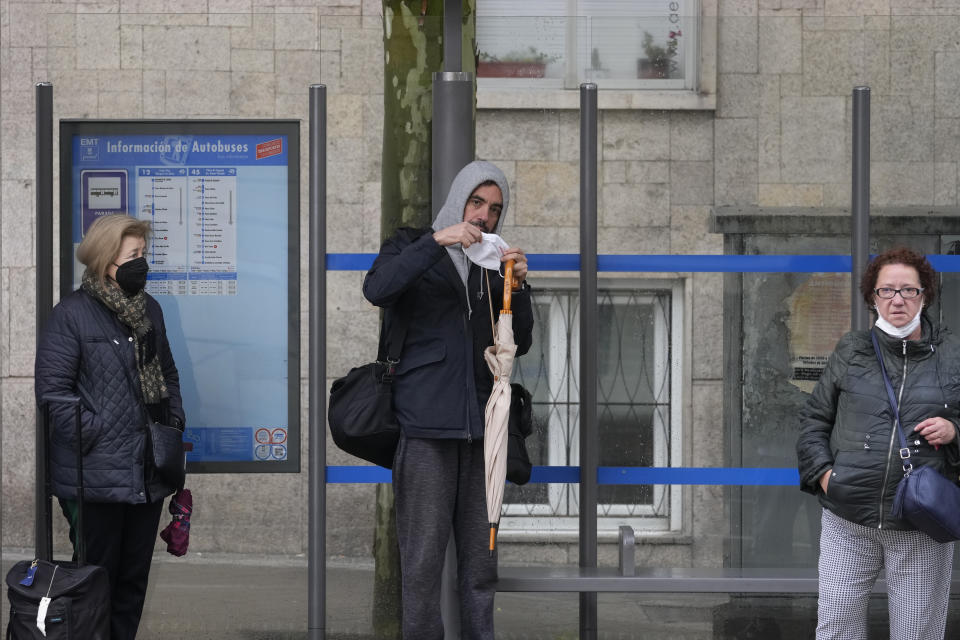 A man puts on his mask to protect against the spread of COVID-19 before boarding a bus in Madrid, Spain, Wednesday, April 20, 2022. Spain is taking another step toward post-pandemic normality by partially ending the obligatory use of masks indoors. A government decree taking effect Wednesday keeps masks still mandatory in medical centers and in all forms of public transport. (AP Photo/Paul White)