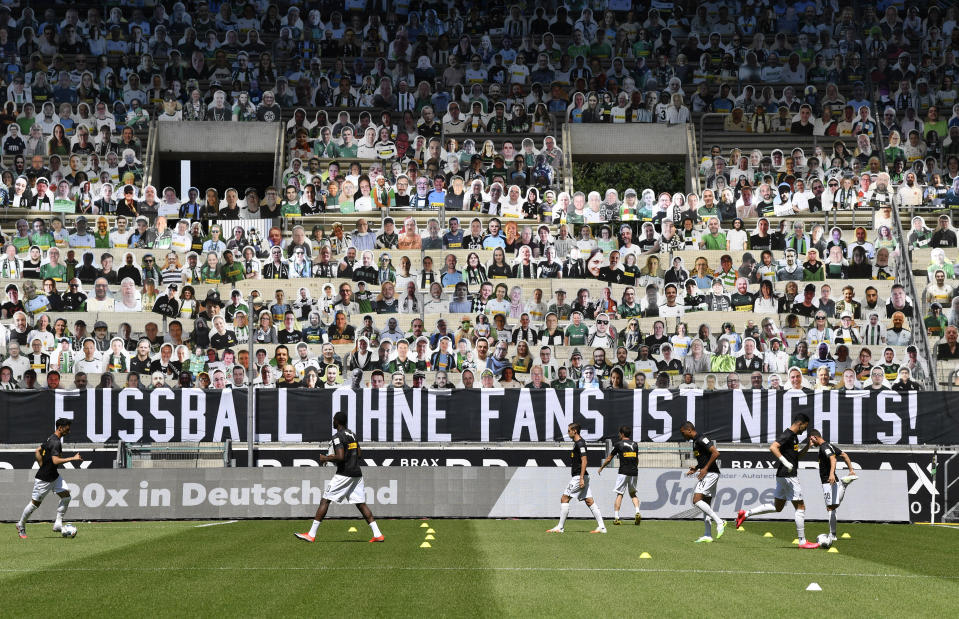 Cardboards with photos of Moenchengladbach fans displayed on the stands during warm up prior the German Bundesliga soccer match between Borussia Moenchengladbach and Union Berlin in Moenchengladbach, Germany, Sunday, May 31, 2020. A banner reads: "For Borussia. Against ghost games!". The German Bundesliga becomes the world's first major soccer league to resume after a two-month suspension because of the coronavirus pandemic. (AP Photo/Martin Meissner, Pool)