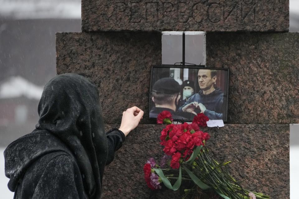 A woman touches a photo of Alexei Navalny after laying flowers paying the last respect to him at the Memorial to Victims of Political Repression in St. Petersburg, Russia on Saturday, Feb. 17, 2024. Russian authorities say that Alexei Navalny, the fiercest foe of Russian President Vladimir Putin who crusaded against official corruption and staged massive anti-Kremlin protests, died in prison. He was 47. (AP Photo/Dmitri Lovetsky)