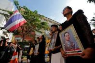 People hold portraits of Thailand's late King Bhumibol Adulyadej as they sing a national anthem at the Siriraj hospital in Bangkok, Thailand, October 14, 2016. REUTERS/Chaiwat Subprasom