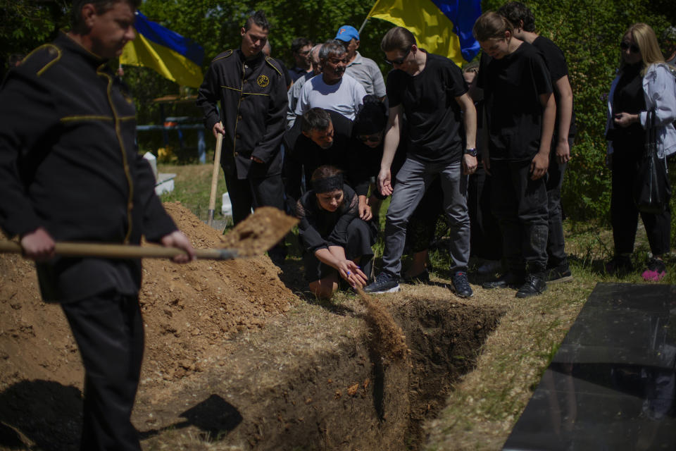 Iuliia Loseva, center, throws earth on top of the coffin of her husband Volodymyr Losev, 38, during his funeral at a cemetery in Zorya Truda, Odesa region, Ukraine, Monday, May 16, 2022. Volodymyr Losev, a Ukrainian volunteer soldier, was killed May 7 when the military vehicle he was driving ran over a mine in eastern Ukraine. (AP Photo/Francisco Seco)