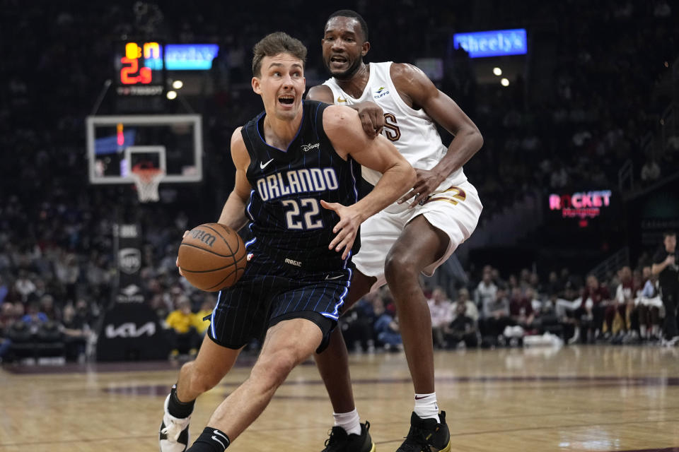 Orlando Magic forward Franz Wagner (22) drives past Cleveland Cavaliers forward Evan Mobley during the first half of an NBA basketball game Thursday, Feb. 22, 2024, in Cleveland. (AP Photo/Sue Ogrocki)