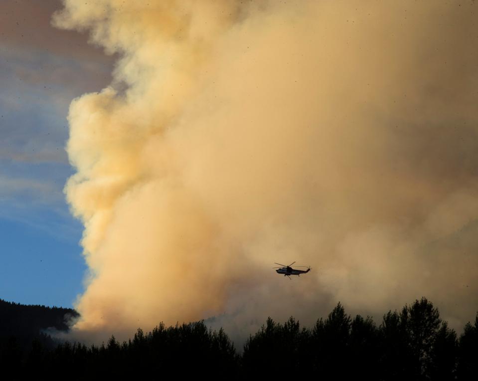 A helicopter drops water on the western side of the Lookout Fire near Rainbow.