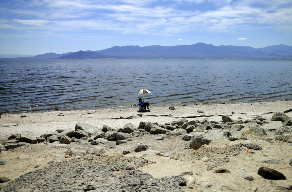 FILE - In this April 30, 2015 file photo, a man fishes for tilapia along the receding banks of the Salton Sea near Bombay Beach, Calif. Work on a multistate plan to address drought on the Colorado River in the U.S. West won't be done to meet a Monday, March 4, 2019 federal deadline. A California irrigation district with the highest-priority rights to the river water says it won't approve the plan without securing money to restore the state's largest lake. The Imperial Irrigation District wants $200 million for the Salton Sea, a massive, briny lake in the desert southeast of Los Angeles. (AP Photo/Gregory Bull, File)