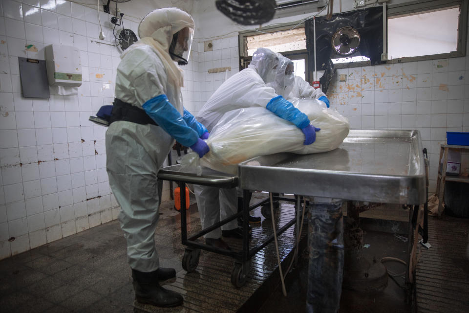 Workers from "Hevra Kadisha," Israel's official Jewish burial society, prepare a body before a funeral procession at a special morgue for COVID-19 victims in the central Israeli city of Holon, near Tel Aviv, Wednesday, Sept. 23, 2020. With Israel facing one of the world's worst outbreaks, burial workers have been forced to wear protective gear and take other safety measures as they cope with a growing number of coronavirus-related deaths. (AP Photo/Oded Balilty)