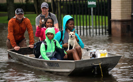 A family is evacuated by boat from the Hurricane Harvey floodwaters in Houston, Texas August 29, 2017. REUTERS/Rick Wilking