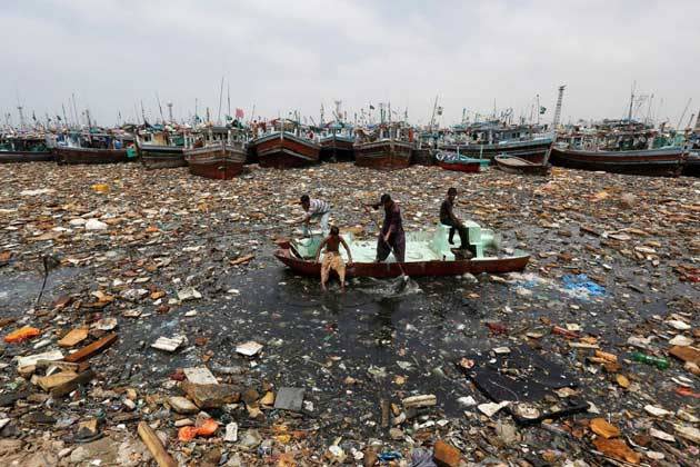 Junge Männer fischen an Bord eines Ruderbootes nach verwertbarem Müll im Hafen von Karatschi in Pakistan. (Bild: Akhtar Soomro/Reuters)