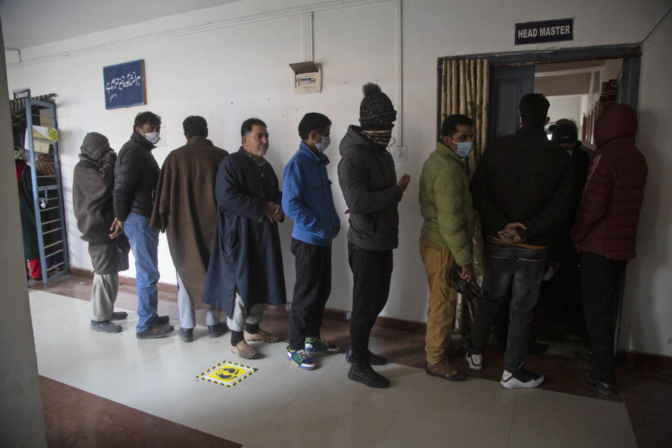 Kashmiris stand in a queue to cast their votes during the first phase of District Development Councils election on the outskirts of Srinagar, Indian controlled Kashmir, Saturday, Nov. 28, 2020. Thousands of people in Indian-controlled Kashmir voted Saturday amid tight security and freezing cold temperatures in the first phase of local elections, the first since New Delhi revoked the disputed region's semiautonomous status. (AP Photo/Mukhtar Khan)