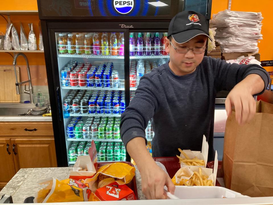 Jason Lin, owner of Crispy Burger, bags a takeout order at the Burlington eatery Feb. 2, 2024.