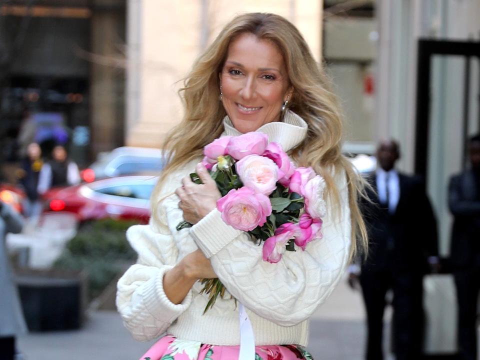Celine Dion holding a bouquet of flowers and smiling in the