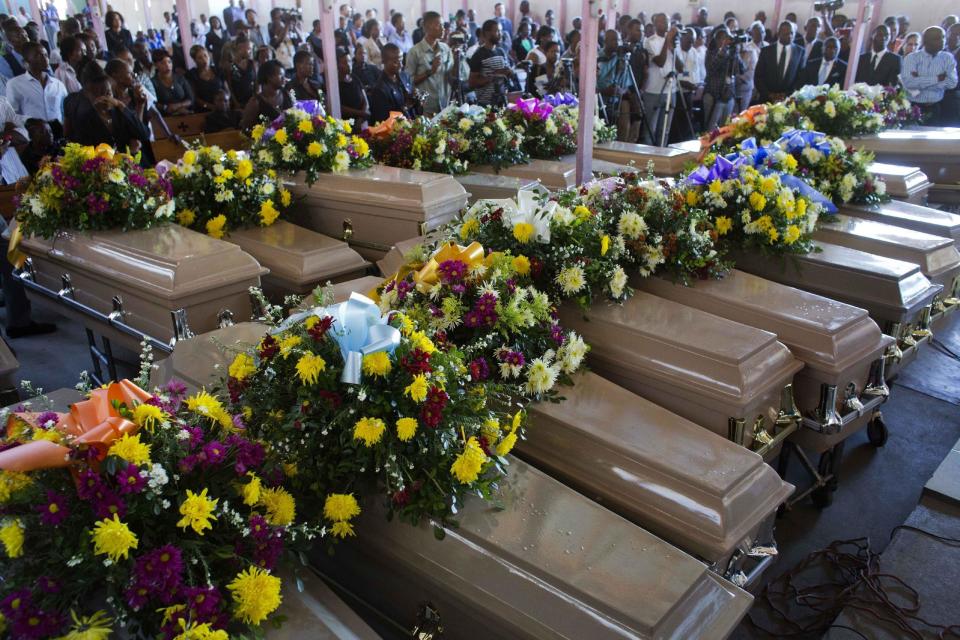 Coffins containing inmates bodies lay inside St. Anne church during the mass burial of inmates who died at the country's largest prison in Port-au-Prince, Haiti. Tuesday Feb. 21, 2017. Relatives wailed in grief or stared stoically as flowers were placed on 20 caskets at a mass funeral for the latest group of inmates who died miserably in Haiti's largest prison, most without ever having been convicted of any crime. ( AP Photo/Dieu Nalio Chery)