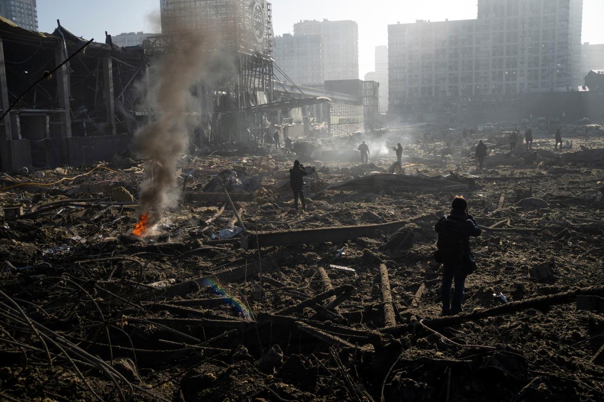 FILE - People survey the destruction amid the smoldering remains of a shopping center in Kyiv, Ukraine, following a shelling by Russian forces on March 21, 2022. 