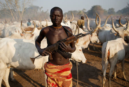 FILE PHOTO - A man from Dinka tribe holds his AK 47 rifle in front of cows in a Dinka cattle herders camp near Rumbek, capital of the Lakes State in central South Sudan December 14, 2013. REUTERS/Goran Tomasevic/File Photo