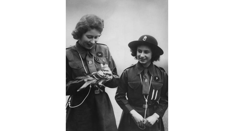 Black-and-white photo of the Queen and Princess Margaret with a pigeon