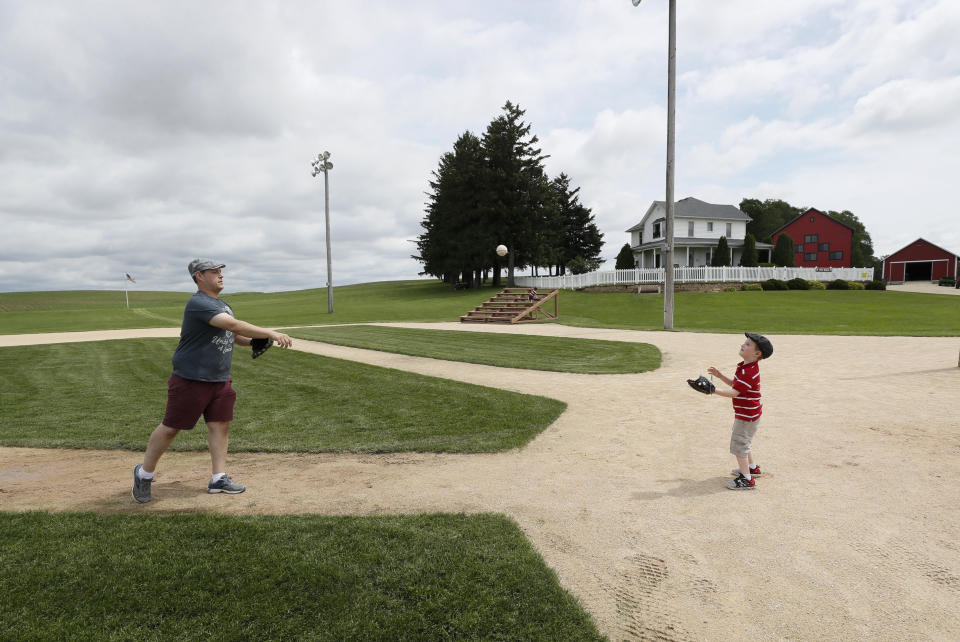 Jeremiah Bronson, of Ames, Iowa, plays catch with his sone Ben, right, on the field at the Field of Dreams movie site, Friday, June 5, 2020, in Dyersville, Iowa. Major League Baseball is building another field a few hundred yards down a corn-lined path from the famous movie site in eastern Iowa but unlike the original, it's unclear whether teams will show up for a game this time as the league and its players struggle to agree on plans for a coronavirus-shortened season. (AP Photo/Charlie Neibergall)