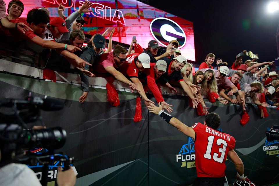Georgia Bulldogs quarterback Stetson Bennett (13) high-fives fans after a NCAA football game on Oct. 29, 2022 at TIAA Bank Field in Jacksonville.The Georgia Bulldogs held off the Florida Gators 42-20.