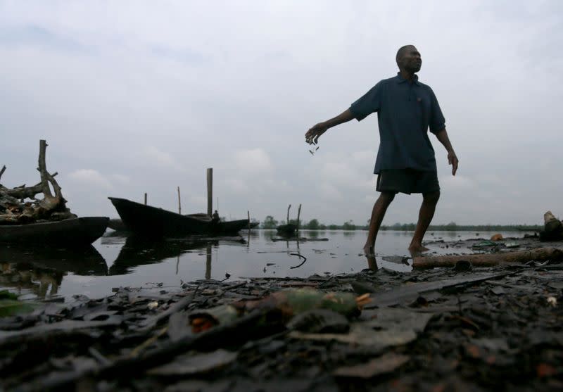 A man throws dead fish back into a polluted river in Ogoniland, Rivers State