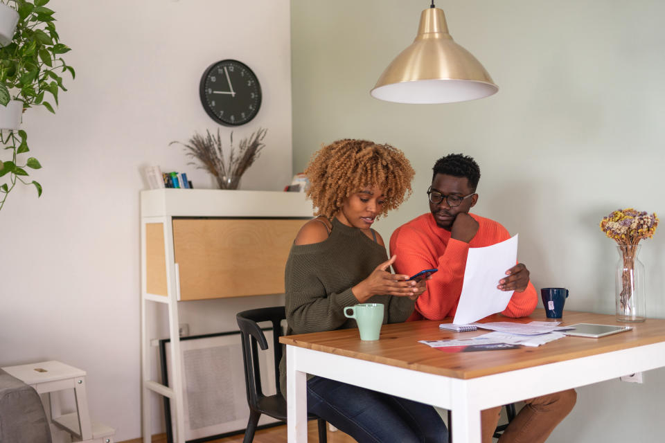 A young African-American couple sits at the dining table and calculates their home finance. 