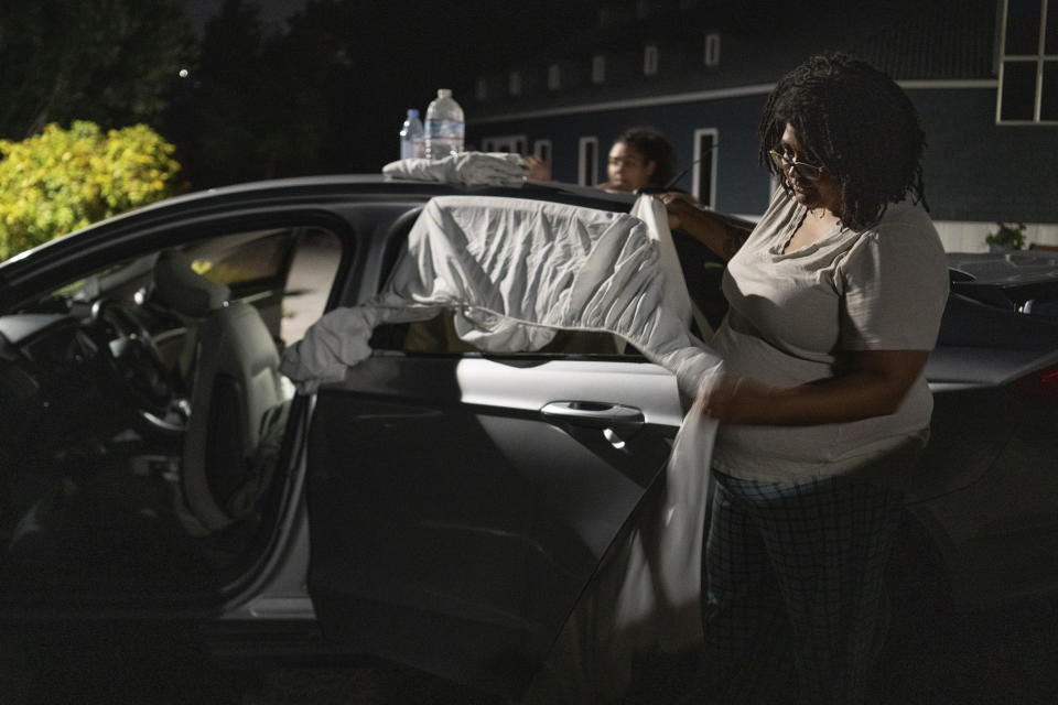 Chrystal Audet y su hija, Cierra, colocan sábanas en las ventanas de su automóvil para crear privacidad, en Kirkland, Washington, el 27 de agosto de 2023. La familia se encuentra entre una cohorte cada vez mayor de trabajadores estadounidenses que viven en sus automóviles. (Ruth Fremson/Los New York Times)