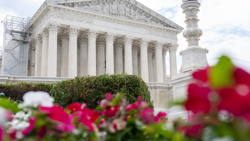 The Supreme Court is seen behind flowers, Tuesday, June 27, 2023, in Washington. The Supreme Court gave a win for the democratic principle of checks and balances in affirming that state courts can weigh in on legislative decisions affecting federal elections, but justices also left an opening for future challenges.