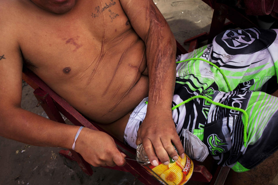 In this Jan. 22, 2013 photo, a man opens a can of peaches on Agua Dulce beach in Lima, Peru. While Lima's elite spends its summer weekends in gate beach enclaves south of the Peruvian capital, the working class jams by the thousands on a single municipal beach of grayish-brown sands and gentle waves. The only barrier to entry to "Agua Dulce" beach is two dollars, the price of bus fare to get there and home. (AP Photo/Rodrigo Abd)