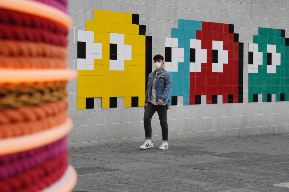 A man wearing a face mask walks along a street in Hong Kong, Friday, Jan. 28, 2022. Hong Kong is cutting the length of mandatory quarantine for people arriving from overseas from 21 to 14 days, even as the southern Chinese city battles a new surge in COVID-19 cases. (AP Photo/Kin Cheung)