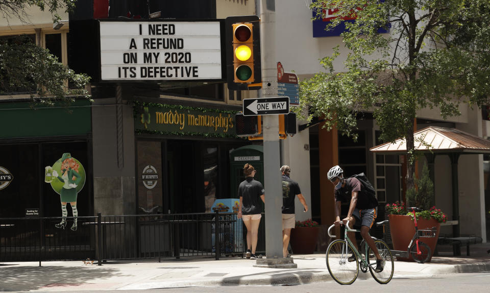 A cyclist wearing masks to protect against COVID-19 passes through downtown San Antonio, Monday, July 20, 2020. Cases of COVID-19 continue to spike in Texas. (AP Photo/Eric Gay)